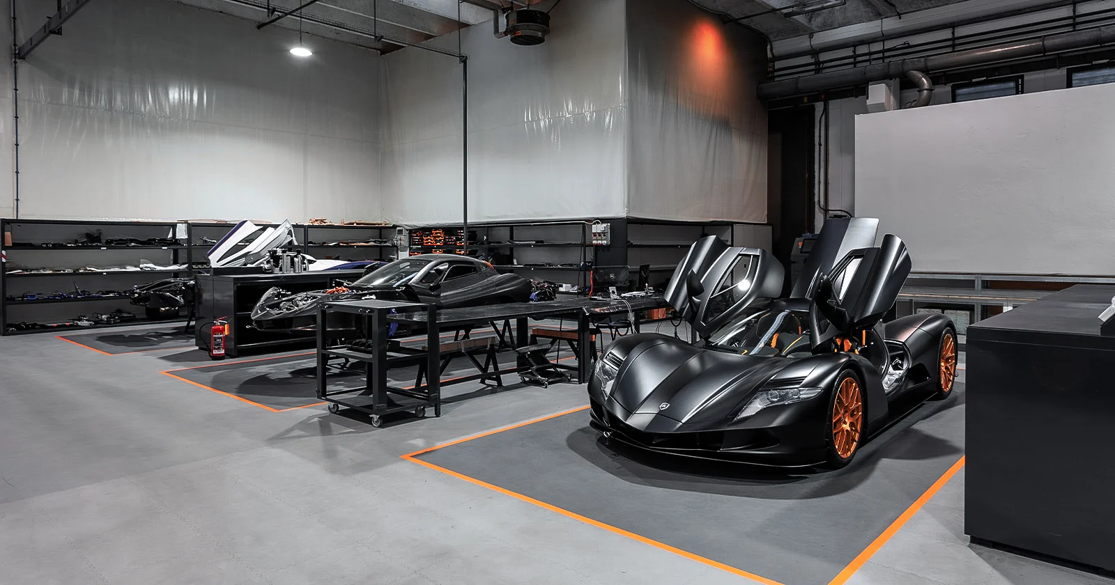 Interior view of well lit car workshop showing two high performance hypercars